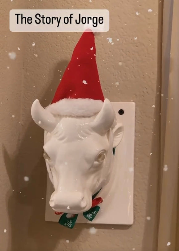 Jorge wearing Santa Hat and Christmas Bow Tie. Jorge is a white ceramic bull head sculpture. Trae Mundt. 